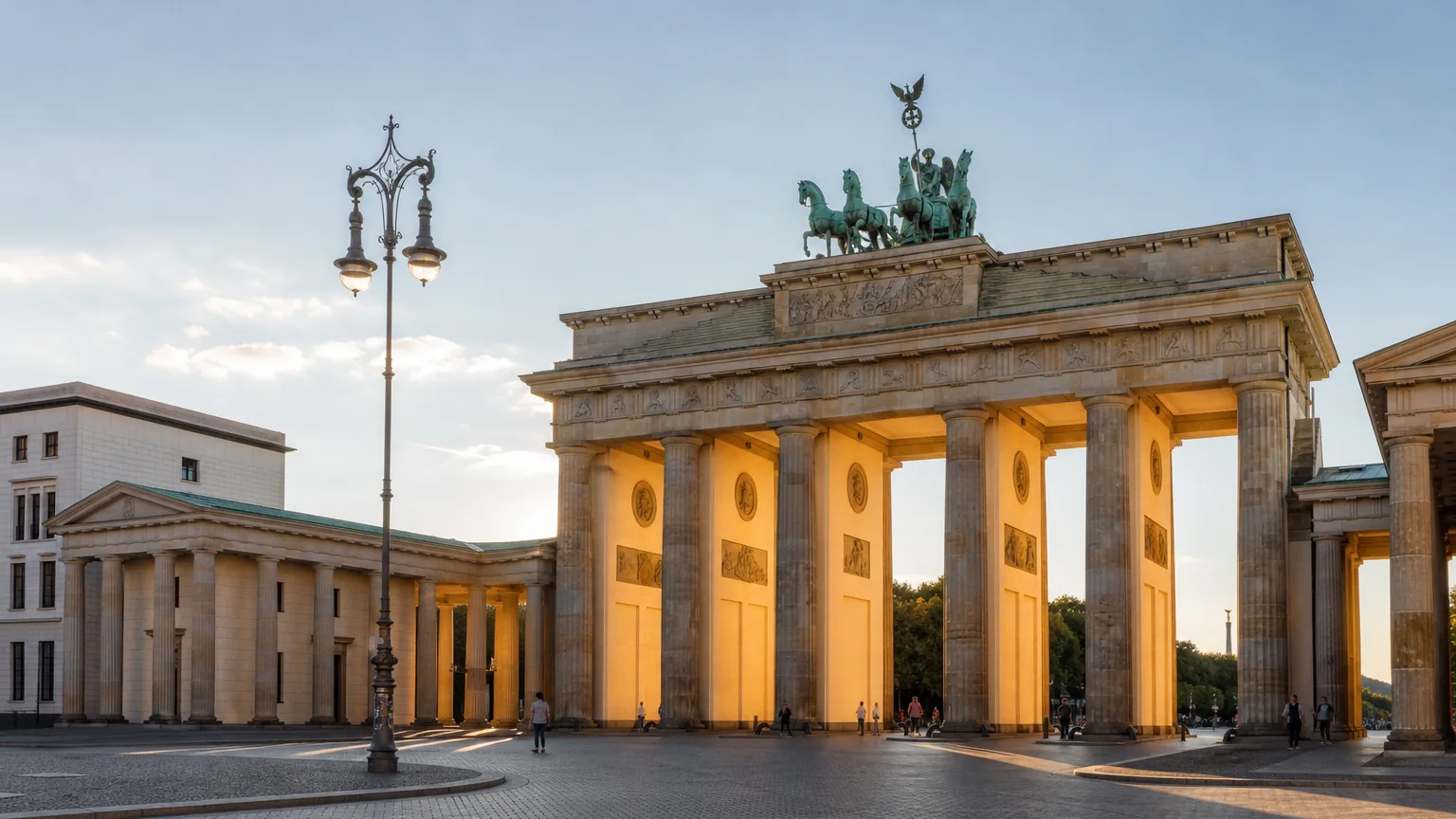 Udsigt over det historiske Brandenburger Tor i Berlin oplyst i den gyldne time med forbipasserende mennesker