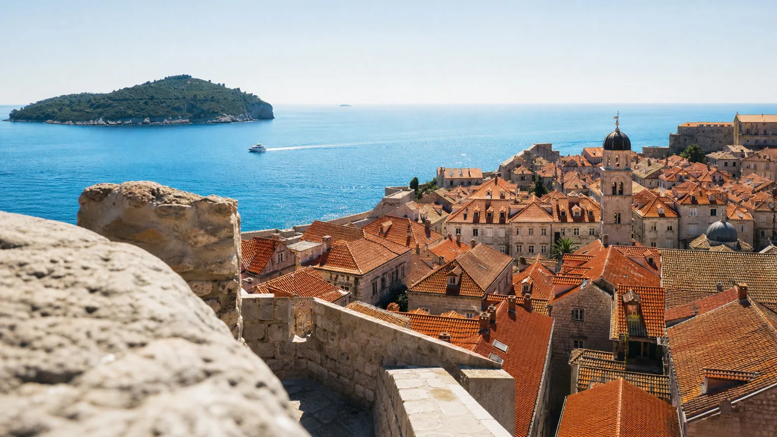 Dubrovniks røde tage og gamle bymure med turkisblåt Adriaterhav og ø i baggrunden