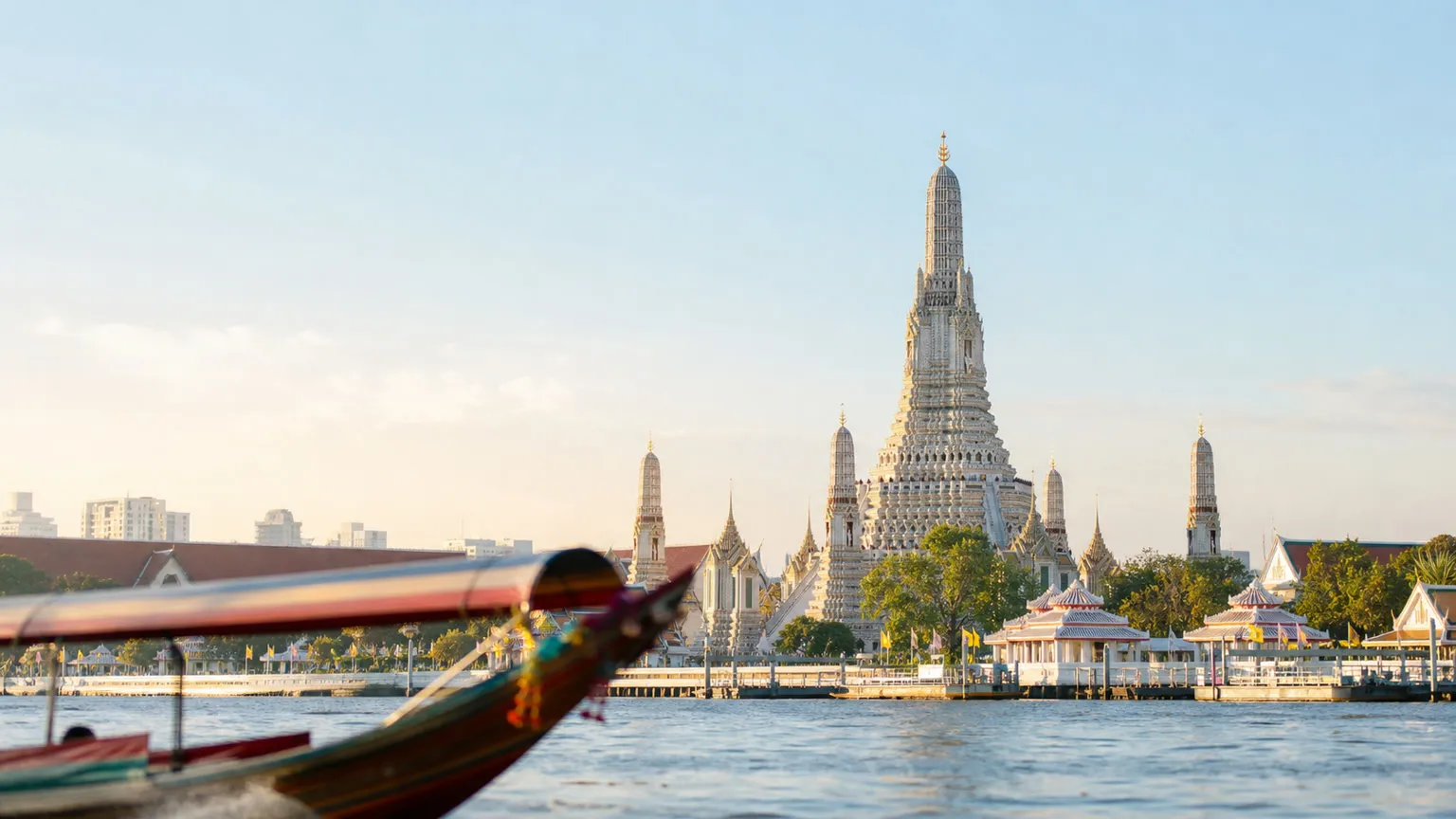 Wat Arun ved Chao Phraya-floden med en sløret longtail-båd i forgrunden i blødt morgenlys