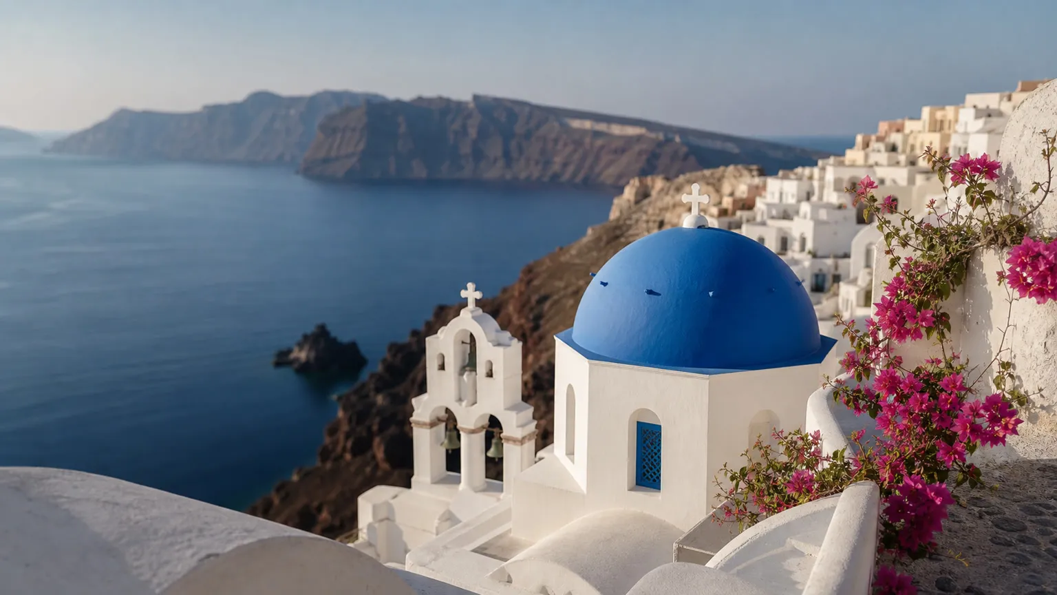 Blåkuplet kirke og hvide huse i Oia med Santorinis caldera og Ægæerhavet i baggrunden