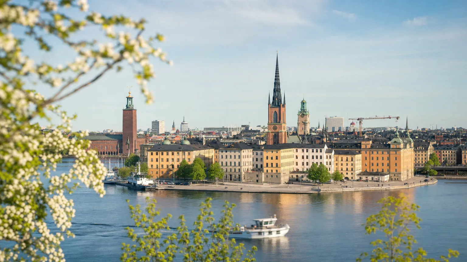 Udsigt over Gamla Stan og Stockholms Stadshus med vand og båd i forgrunden på en lys forårsdag