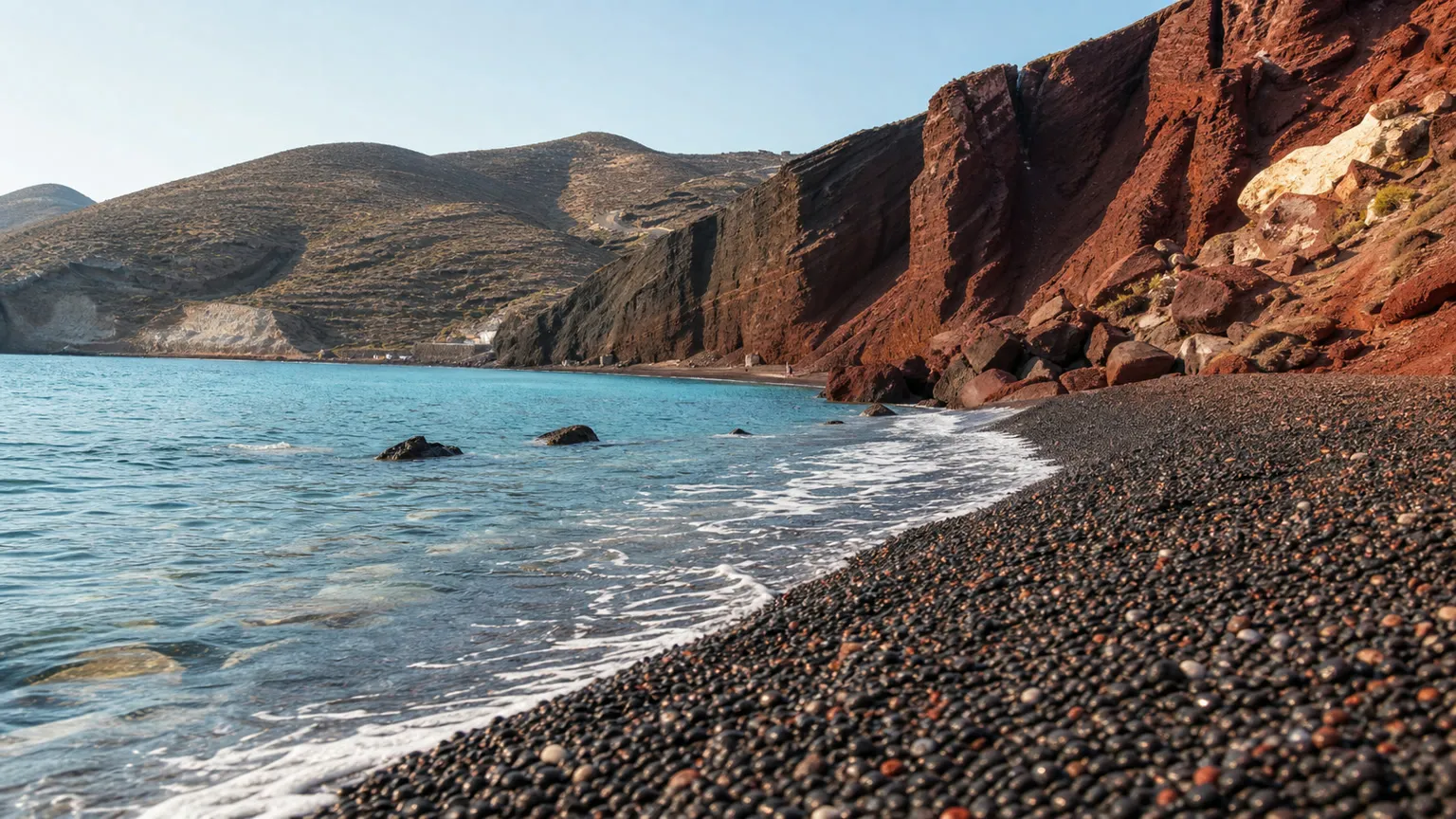 Sort vulkansk strand på Santorini med turkisblåt hav og røde klipper ved Red Beach